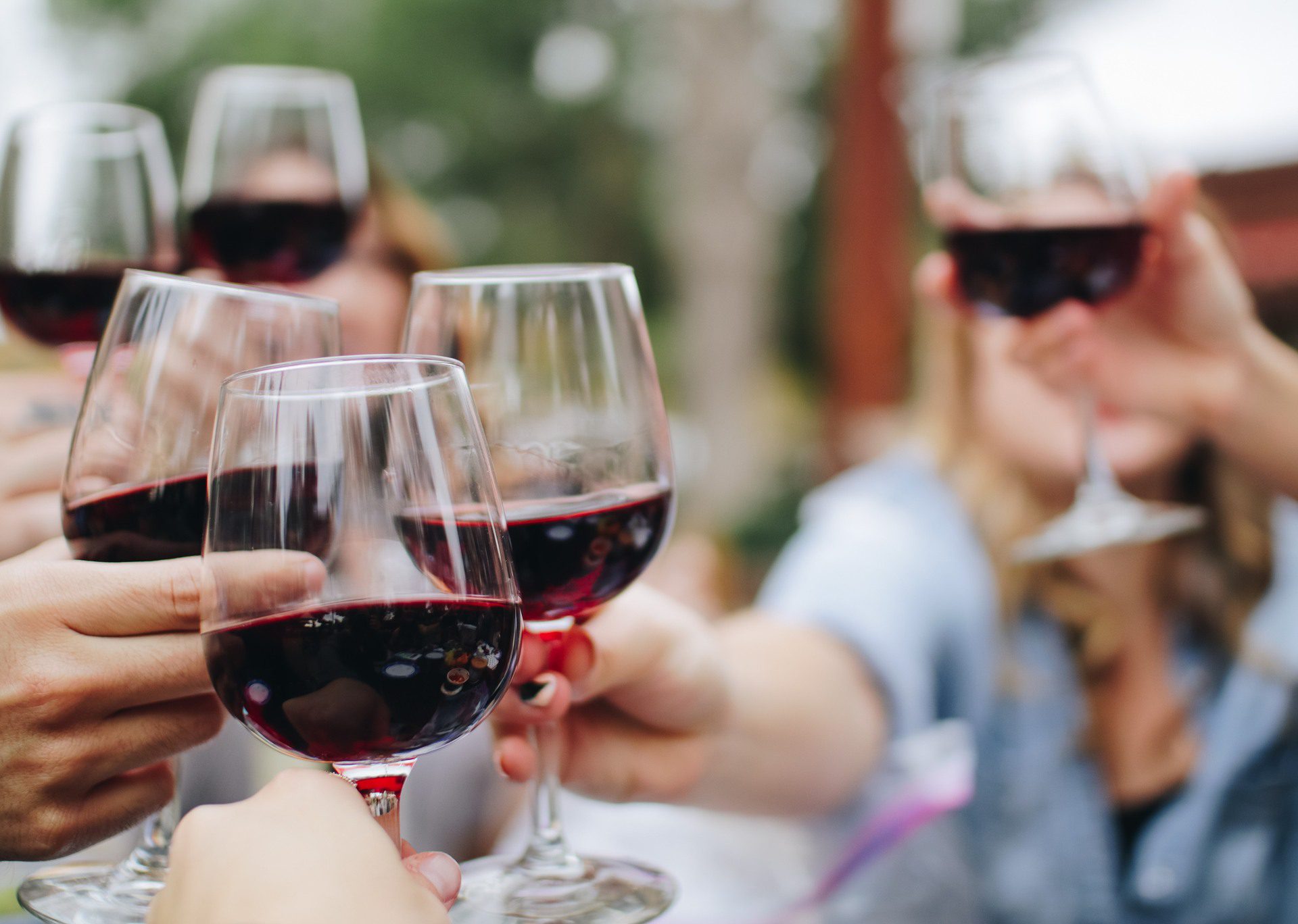 People toasting with red wine glasses